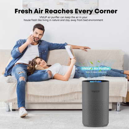 Air purifier on a living room floor with a couple sitting on a couch